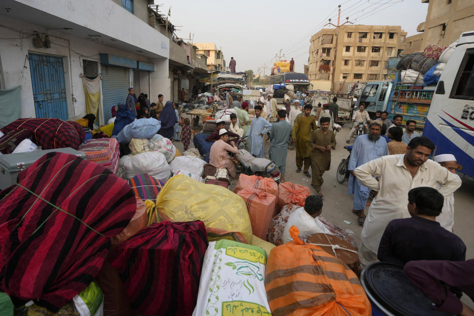 Familias afganas esperan para subir a autobuses que los lleven de regreso a su país, Karachi, Pakistán, el 30 de octubre de 2023. (AP Foto/Fareed Khan).