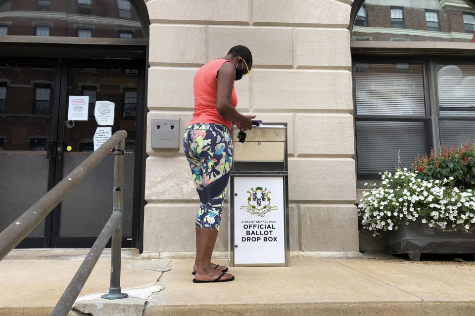 FILE - In this Aug. 6, 2020, file photo, Katrina McKelvin of New London, Conn., deposits her absentee ballot for the Aug. 11 primary in a special box that has been set up outside the New London City Hall. As Republicans roll back access to the ballot, Democratic lawmakers have been quietly moving to expand voting rights. (AP Photo/Susan Haigh, File)