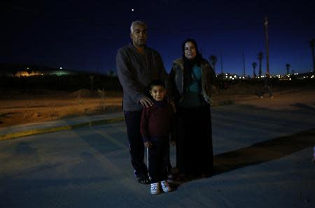 Syrian migrants Djamaar Khedr (L) his wife Nejmah and their son Qusai pose for a photograph outside a refugee centre in Spain's north African enclave Melilla December 5, 2013. REUTERS/Juan Medina