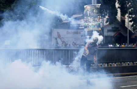 Demonstrator throws back a tear gas canister while clashing with the riot police during a rally. REUTERS/Marco Bello