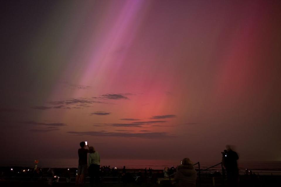 La gente visita el faro de St Mary en Whitley Bay para ver la aurora boreal el 10 de mayo de 2024 en Whitley Bay, Inglaterra. (Foto de Ian Forsyth/Getty Images)