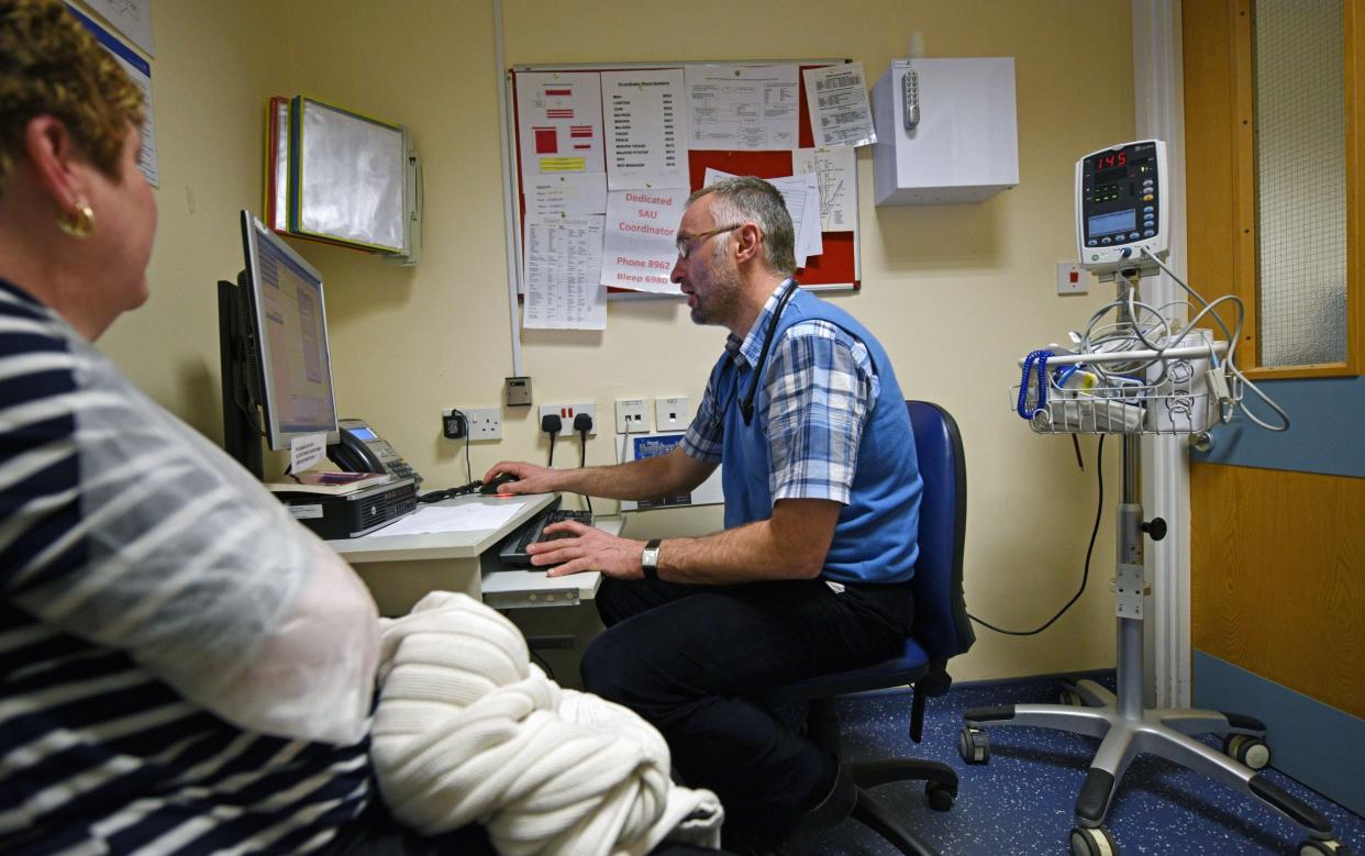 A GP seeing a patient at an A&E department in Wigan. Last week GPs voted in favour of industrial action over a new contract which forces practices to open on Saturdays - AFP 