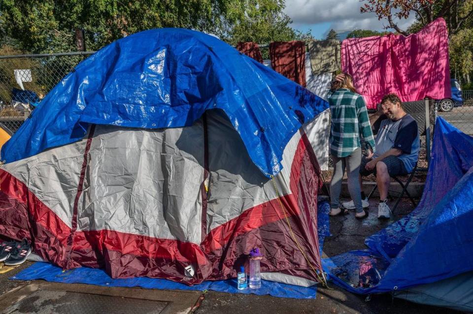 Jeff McDowell, 50, and his wife, Ashleigh McDowell, 29, take a break from hanging blankets and clothing to dry on Monday, Oct. 25, 2021, at the homeless Safe Ground near Eighth and W streets in Sacramento. They said their tent collapsed during Sunday’s storm and they had to buy another one.