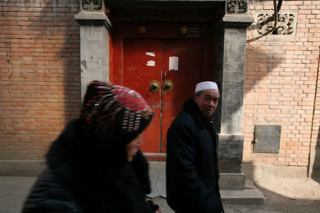 A man and a woman walk through a neighbourhood in China's Linxia, Gansu province, home to a large population of ethnic minority Hui Muslims, February 3, 2018. Picture taken February 3, 2018. REUTERS/Michael Martina