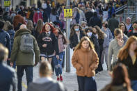 People pass a social distancing sign in Cardiff, where restrictions across Wales have been relaxed following a two-week "firebreak" lockdown, Sunday, Nov. 22, 2020. First Minister Mark Drakeford has said there is evidence that the firebreak in Wales had successfully had an impact on lowering the rate of coronavirus transmission. (Ben Birchall/PA via AP)