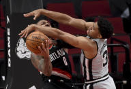 Portland Trail Blazers guard Damian Lillard, left, is fouled by San Antonio Spurs forward Keldon Johnson, right, as he drives to the basket during the second half of an NBA basketball game in Portland, Ore., Monday, Jan. 18, 2021. (AP Photo/Steve Dykes)