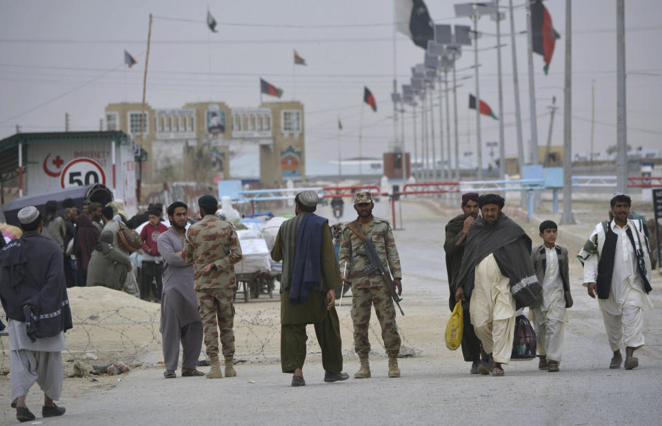 Pakistani paramilitary soldiers stand guard while people wait for opening border crossing, in Chaman, Pakistan, Monday, March 20, 2017. Pakistan's prime minister ordered the reopening of the country's border with Afghanistan on Monday, ending a protracted closure that has cost businesses on both sides millions of dollars and deepened tensions between the two neighbors. (AP Photo/Matiullah Achakzai)