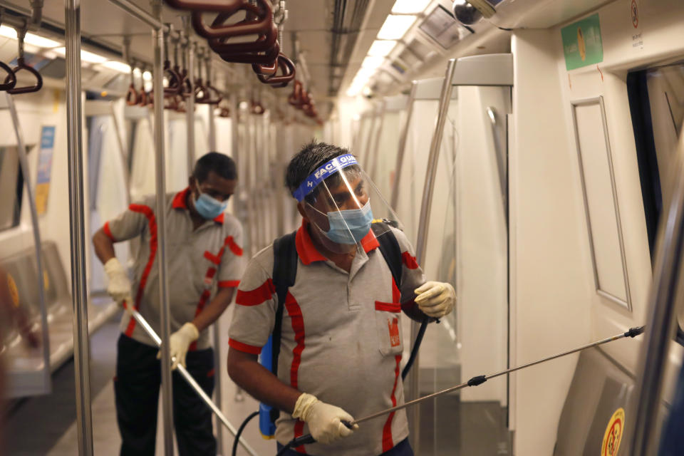 Workers sanitize a metro coach in New Delhi, India, Thursday, Sept. 3, 2020. Delhi Metro will open its services in a phased manner from Sept. 7, even as India has been reporting the highest single-day caseload in the world every day for more than three weeks and is the third worst-hit country behind the United States and Brazil. The country's economy contracted by 23.9% in the April-June quarter, India's worst performance in at least 24 years.(AP Photo/Manish Swarup)