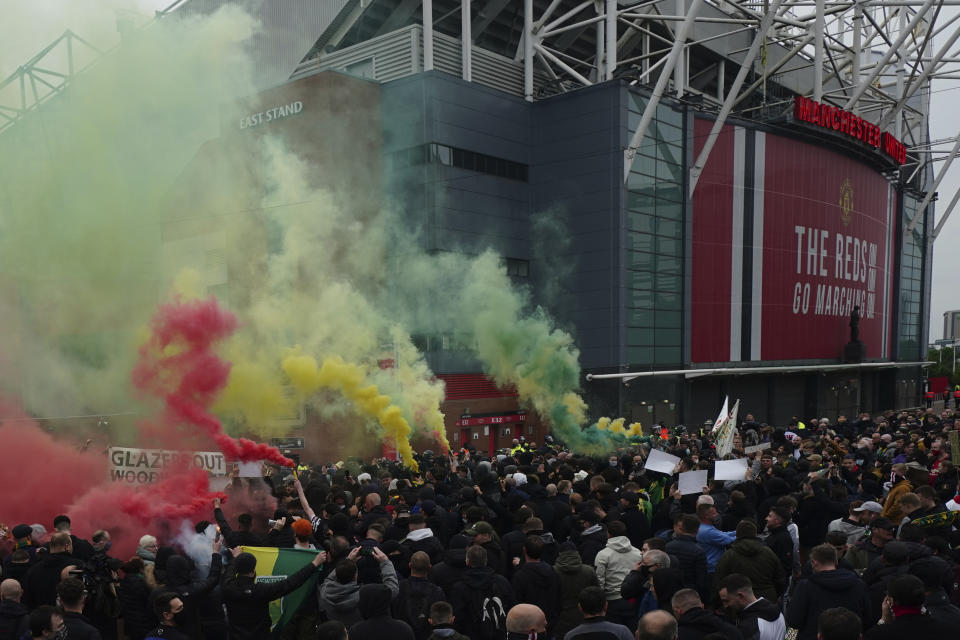 Manchester United fans let off flares as they protest against the Glazer family, the American owners of Manchester United, before their English Premier League soccer match against Liverpool at Old Trafford stadium in Manchester, England, Thursday, May 13, 2021. (AP Photo/Jon Super)