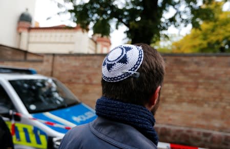 A man wearing a kippah is seen next to a police vehicle outside the synagogue in Halle