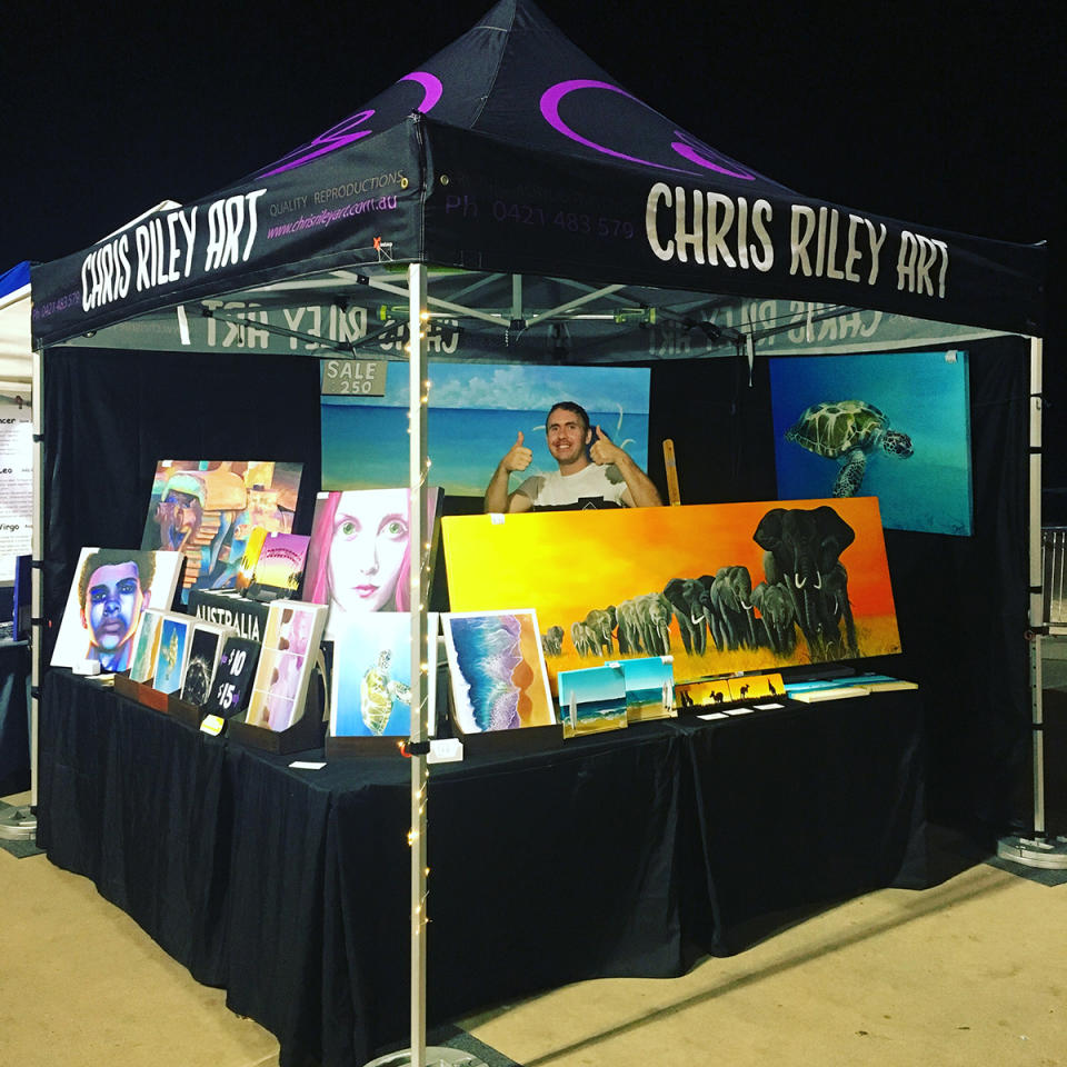 Australian painter Chris Riley selling his art at a market stall. Photo: supplied.