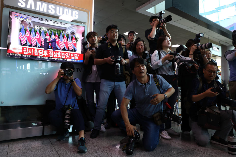 Photographers gather next to a TV while&nbsp;Trump and Kim meet.