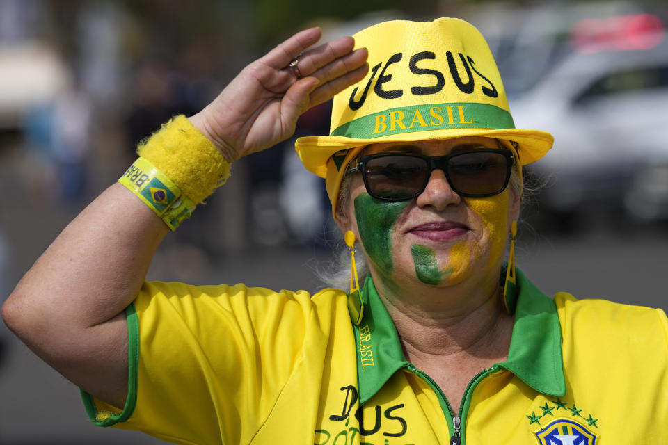 A woman salutes during a campaign event for Brazil's President Jair Bolsonaro, who is running for reelection, in Brasilia, Brazil, Saturday, Oct. 29, 2022. Bolsonaro is facing former President Luiz Inacio Lula da Silva in a runoff election set for Oct. 30. (AP Photo/Eraldo Peres)