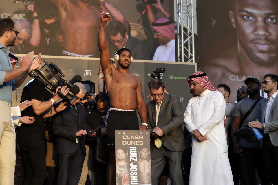 Heavyweight boxer Anthony Joshua of Britain, center, raises his hand during a weigh-in at Faisaliah Center, in Riyadh, Saudi Arabia, Friday, Dec. 6, 2019. The first ever heavyweight title fight in the Middle East, has been called the "Clash on the Dunes." Will take place at the Diriyah Arena on Saturday. (AP Photo/Hassan Ammar)