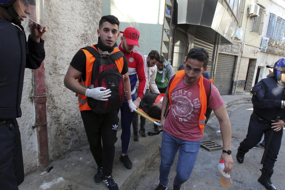 Protestors carry a stretcher with an injured demonstrator during clashes with police officers as part of a demonstration against the country's leadership, in Algiers,Algeria, Friday, April 12, 2019. Heavy police deployment and repeated volleys of water cannon didn't deter masses of Algerians from packing the streets of the capital Friday, insisting that their revolution isn't over just because the president stepped down. (AP Photo/ Fateh Guidoum)