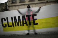 A man, wearing a mask to prevent the spread of the coronavirus, holds a banner that reads: "United for climate" during a small climate change protest in downtown Brussels, Friday, Sept. 25, 2020. (AP Photo/Francisco Seco)