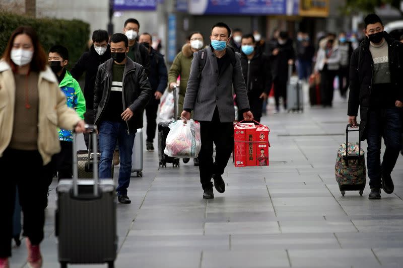 Passengers wearing masks walk outside the Shanghai railway station in Shanghai