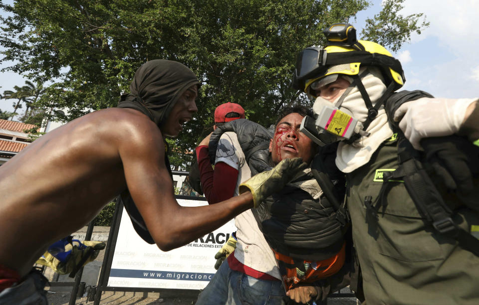 FILE - In this Feb. 25, 2019 file photo, a Venezuelan youth, injured in clashes with Venezuelan National Guardsmen, is carried to a safe zone, at the Simon Bolivar International Bridge in La Parada, Colombia, on the border with Venezuela. At least four people were killed and 300 injured when clashes broke out between state security forces, armed pro-government groups and the opposition as they tried to bring U.S. humanitarian aid into the country despite President Nicolas Maduro's objections. (AP Photo/Fernando Vergara, File)