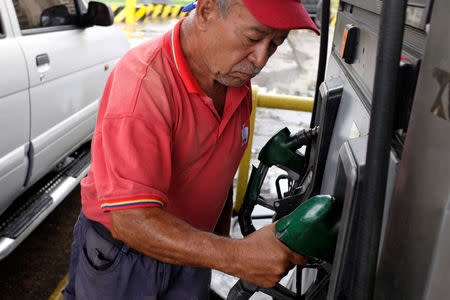 A gas station worker handles the nozzle of a fuel dispenser at a gas station of the Venezuelan state-owned oil company PDVSA in Caracas, Venezuela September 24, 2018. REUTERS/Marco Bello