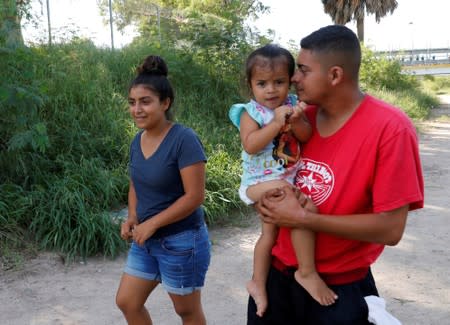 Honduran migrants Marvin Madrid and his new wife Dexy Maldonado walk along the Rio Bravo near an encampment in Matamoros