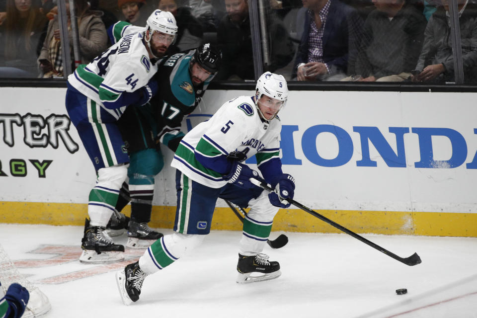 Vancouver Canucks' Derrick Pouliot, right, moves the puck past teammate Erik Gudbranson, left, and Anaheim Ducks' Ryan Kesler during the third period of an NHL hockey game Wednesday, Feb. 13, 2019, in Anaheim, Calif. The Ducks won 1-0. (AP Photo/Jae C. Hong)