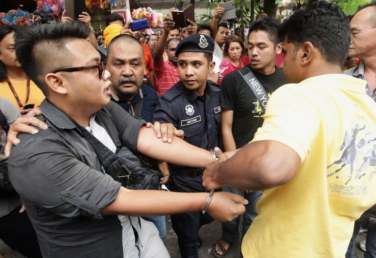 Malaysian Police drag away a protestor (L) during a flash-mob protest in Kuala Lumpur on June 15, 2013. Malaysian police arrested 15 people over a flash-mob protest held to build support for a planned June 22 opposition rally against alleged fraud in elections held last month