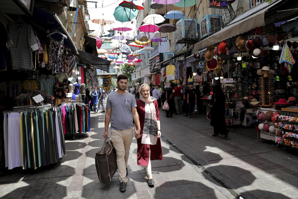 In this July 3, 2019 photo, newly married Iranian couple, Mohammad Davoodi, 28, and his wife Mahsa Asadzadeh, 20, walk in a shopping center in downtown Tehran, Iran. Iran’s large middle class has been hit hard by the fallout from unprecedented U.S. sanctions, including the collapse of the national currency. Perhaps most devastating has been the doubling of housing prices. More newlyweds move in with their families to save money. (AP Photo/Ebrahim Noroozi)