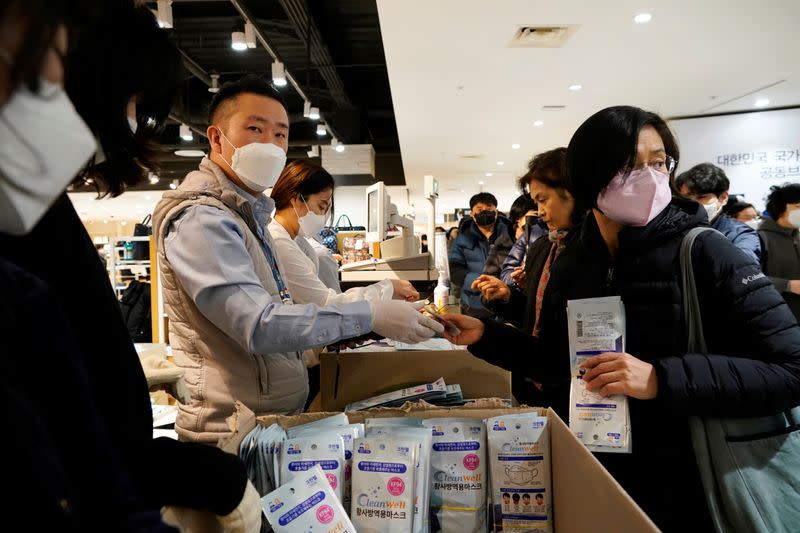 People wearing masks to prevent contracting the coronavirus wait in a line to buy masks in front of a department store in Seoul