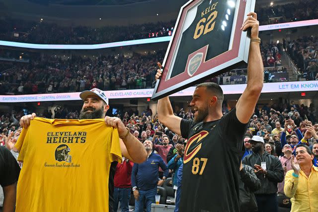 <p>Jason Miller/Getty </p> Jason Kelce and Travis Kelce wave to the fans during the first quarter of a game between the Cleveland Cavaliers and the Boston Celtics on March 5, 2024.