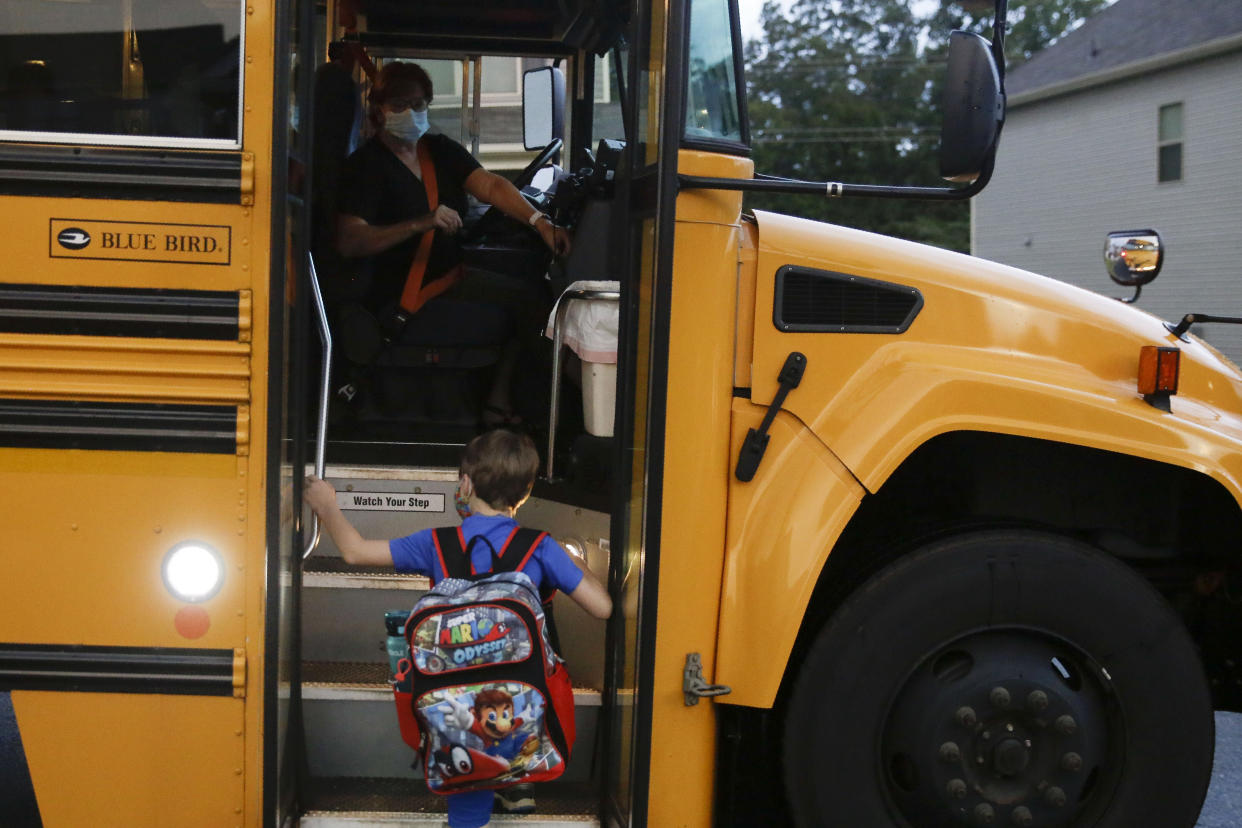 Paul Adamus, 7, climbs the stairs of a bus before the fist day of school on Monday, Aug. 3, 2020, in Dallas, Ga.&#xa0; (AP Photo/Brynn Anderson)