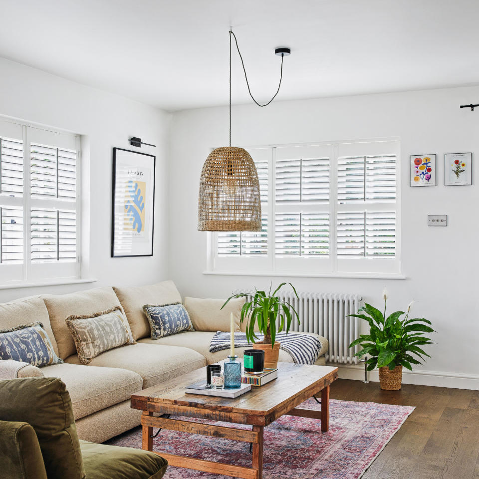 White living room with light coloured sofa, wooden coffee table, and colourful rug