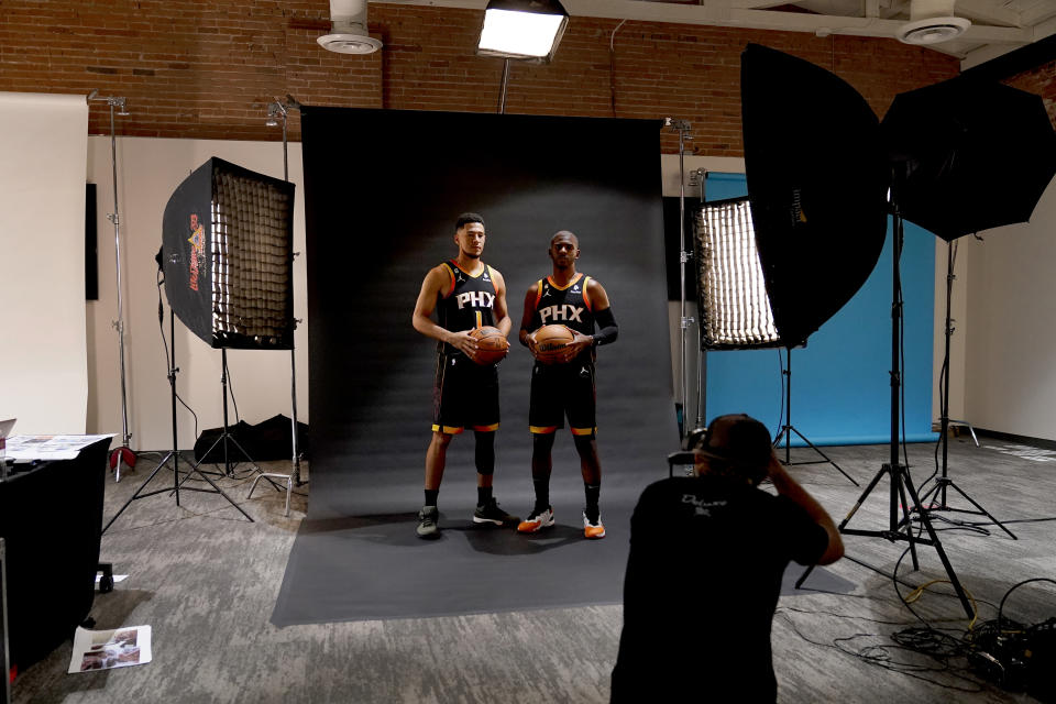 Phoenix Suns' Chris Paul, right, and Devin Booker pose for a photo with team photographer Barry Gossage during an NBA basketball media day, Monday, Sept. 26, 2022, in Phoenix. (AP Photo/Matt York)