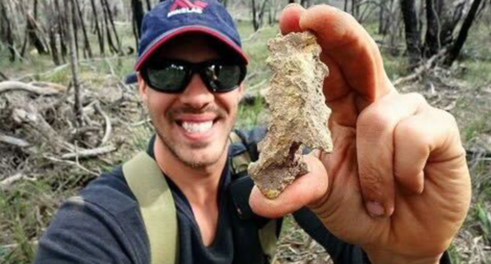 Angus James dug holding his five ounce nugget, with bushland in the background.
