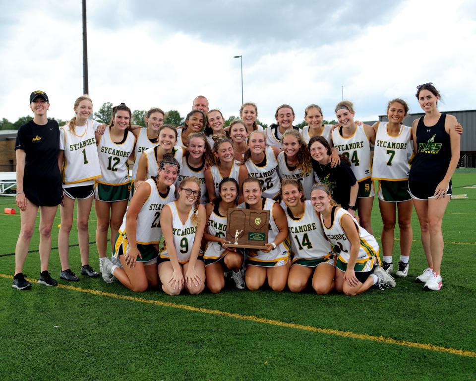 Sycamore players celebrate with the regional championship trophy in the girls Division I lacrosse regional final game between Sycamore and Mason high schools May 25, 2022.