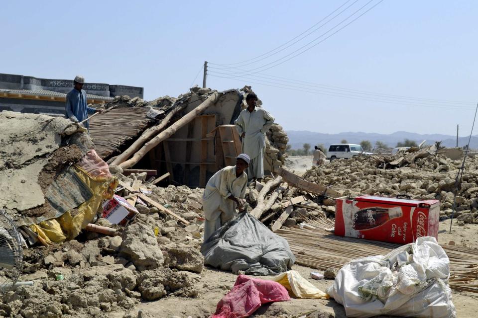 Survivors collect their belongings near the rubble of a mud house after it collapsed following an earthquake in the town of Awaran, southwestern Pakistani province of Baluchistan, September 25, 2013. The death toll from a powerful earthquake in southwest Pakistan rose to 327 on Wednesday after hundreds of mud houses collapsed on residents throughout the remote and thinly populated area, local officials said, REUTERS/Naseer Ahmed