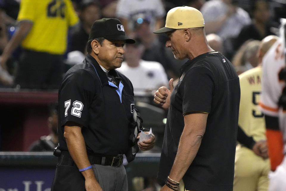 Umpire Alfonso Marquez (72) talks with Arizona Diamondbacks bench coach Jeff Banister, right, after throwing out Christian Walker for arguing balls and strikes in the sixth inning during a baseball game against the San Francisco Giants, Friday, May 12, 2023, in Phoenix. (AP Photo/Rick Scuteri)