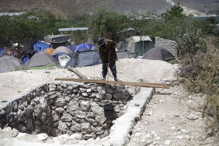 A man pulls out a bucket of rocks from the bottom of a latrine he and others are building at a camp for returned Haitians and Haitian-Dominicans, behind a school near the border between Dominican Republic and Haiti, in Malpasse, Haiti, August 3, 2015. REUTERS/Andres Martinez Casares