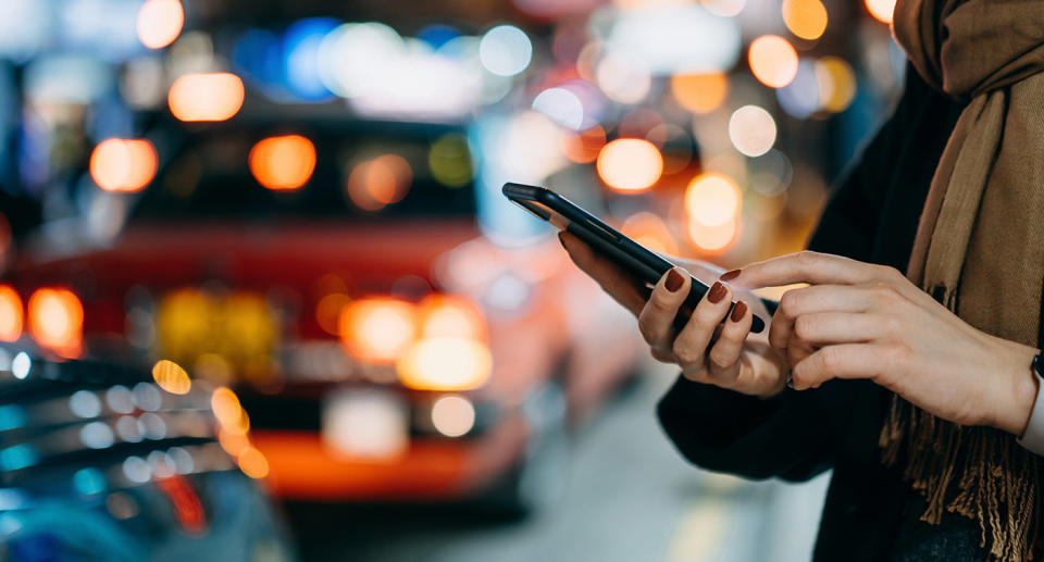 Woman on city street booking Uber