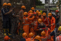 A police officer claps as a woman is rescued from the debris of a four-story residential building that collapsed in Mumbai, India, Tuesday, June 28, 2022. At least three people died and more were injured after the building collapsed late Monday night. (AP Photo/Rafiq Maqbool)