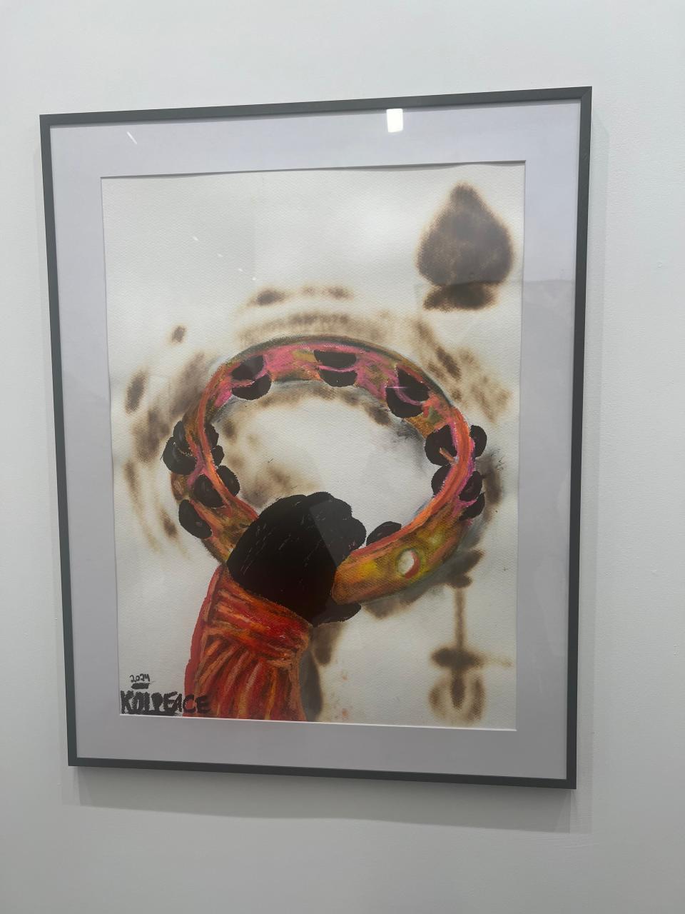 Framed artwork featuring an abstract circular design, possibly suggesting travel themes. Artist's signature in the corner