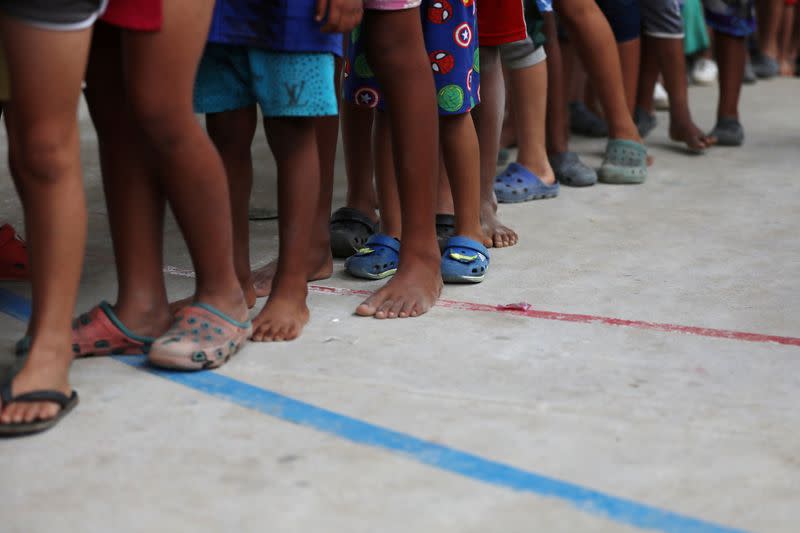 Venezuelan migrant children line up inside a coliseum where a temporary camp has been set up, after fleeing their country due to military operations, according to the Colombian migration agency, in Arauquita