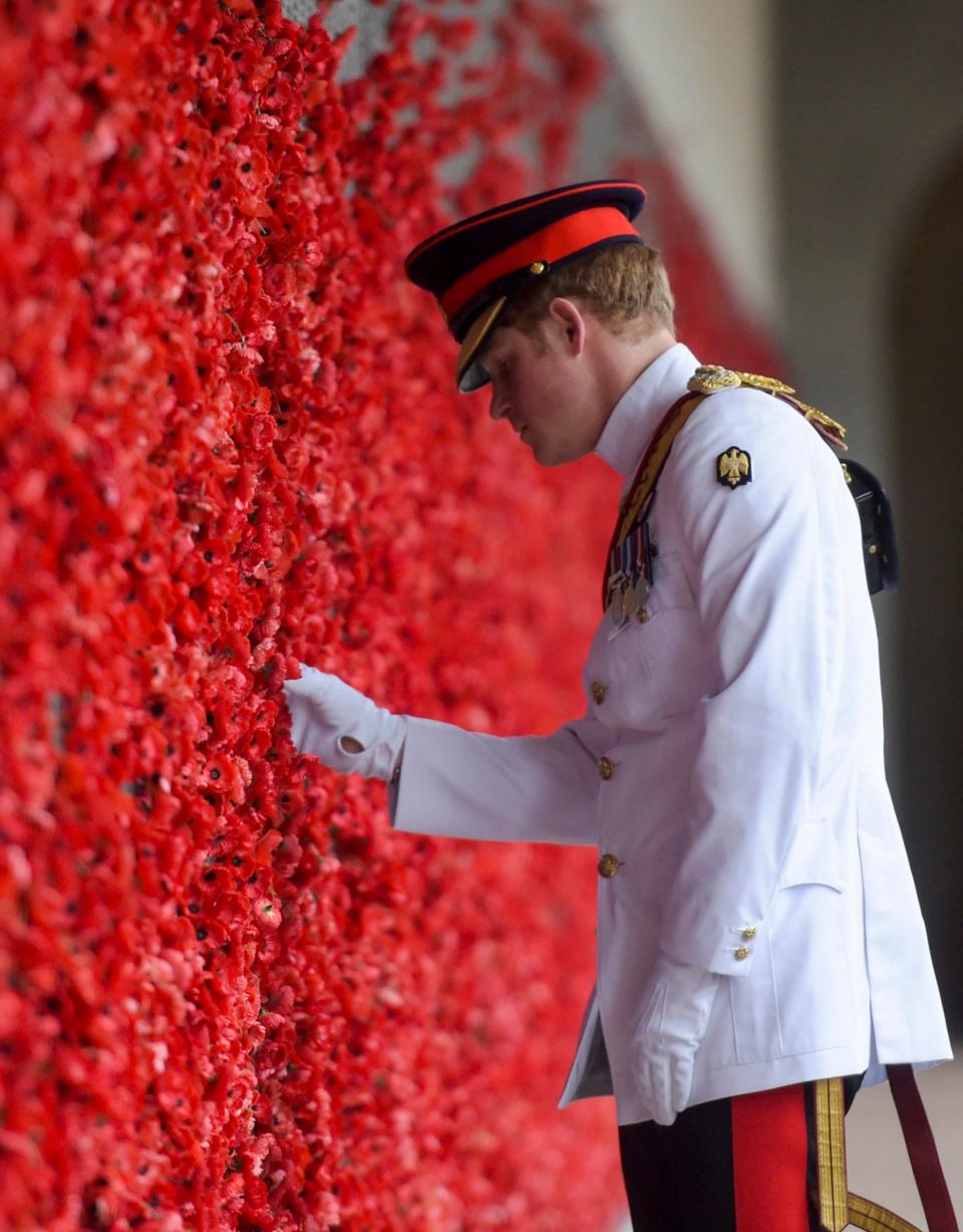 Prince Harry visits the Australian War Memorial in Canberra, Australia, Monday, April 6, 2015, laying a poppy on a bright red wall of poppies, wearing a white service uniform - Credit: Lukas Coch/AP