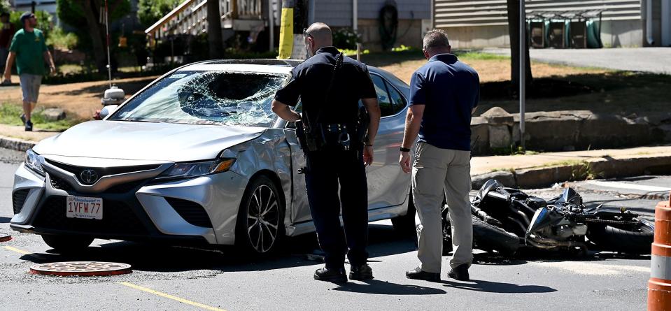 Police examine the damage to a car and motorcycle following a collision between the two vehicles at the intersection of Purchase and Fountains streets in Milford, Aug. 12, 2022.