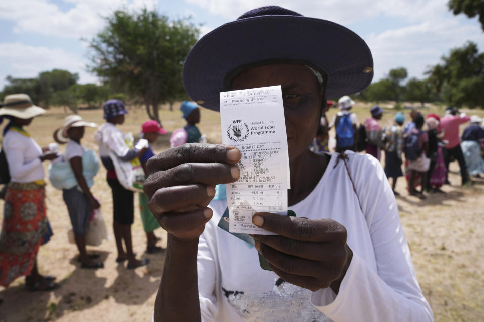 A woman shows her slip while waiting in a queue to receive food aid in Mangwe district in southwestern Zimbabwe, Friday, March, 22, 2024. A new drought has left millions facing hunger in southern Africa as they experience the effects of extreme weather that scientists say is becoming more frequent and more damaging. (AP Photo/Tsvangirayi Mukwazhi)