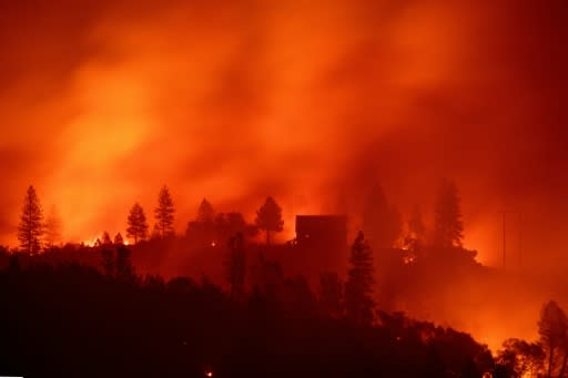 Flames from the Camp Fire burn near a home atop a ridge near Big Bend, California