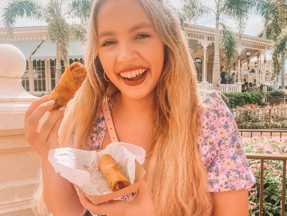 kayleigh price holding a cheese-burger egg roll at magic kingdom in disney world