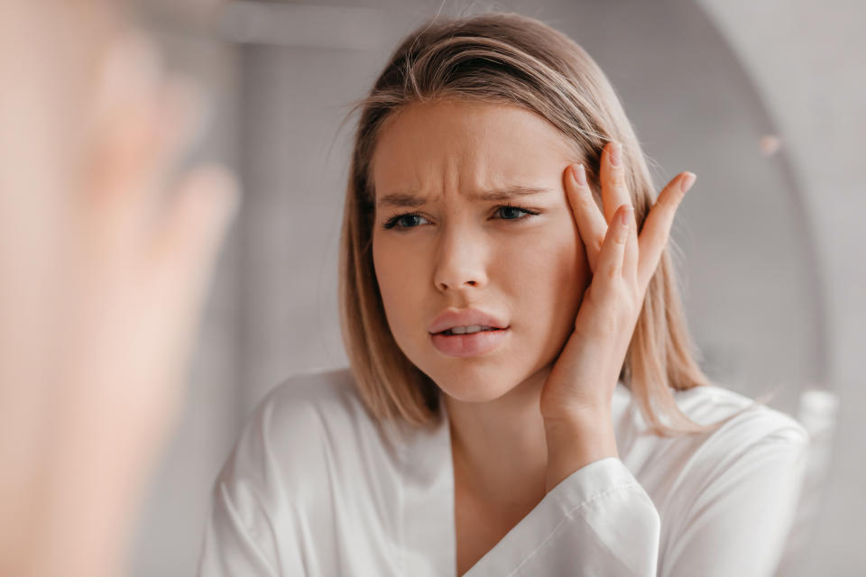 woman looking at her forehead lines in the mirror