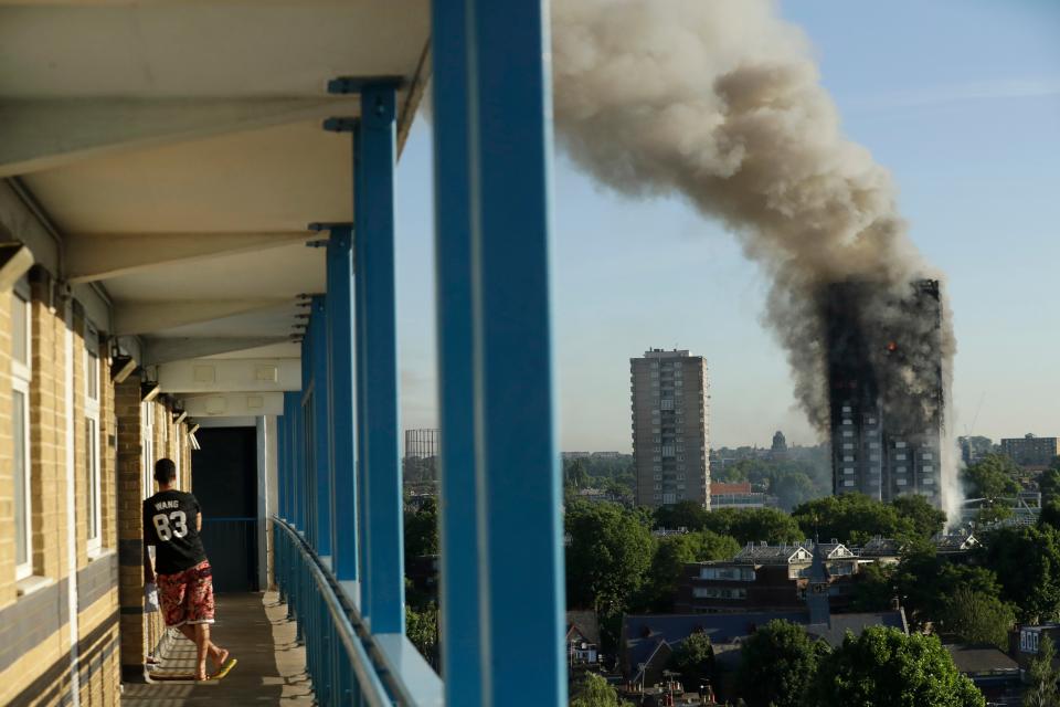 A resident in a nearby building watches smoke rise from the Grenfell Tower building on fire in London (Copyright 2017 The Associated Press. All rights reserved.)