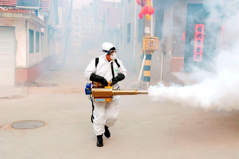 Worker in protective suit disinfects the Dongxinzhuang village, as the country is hit by the new coronavirus, in Qingdao