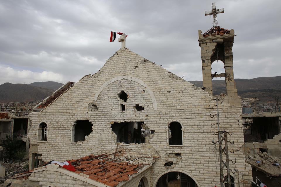 FILE - This May 18, 2017 file photo, shows a Syrian flag raised over the damaged Saint Mary Roman Orthodox church at the mountain resort town of Zabadani in the Damascus countryside, Syria. The Qatar-based Syrian Network for Human Rights, a Syrian war monitor associated with the opposition said in its report Monday, Sept. 9, 2019, that over 120 Christian places of worship have been damaged or destroyed by all sides in the country’s eight-year conflict. (AP Photo/Hassan Ammar, File)